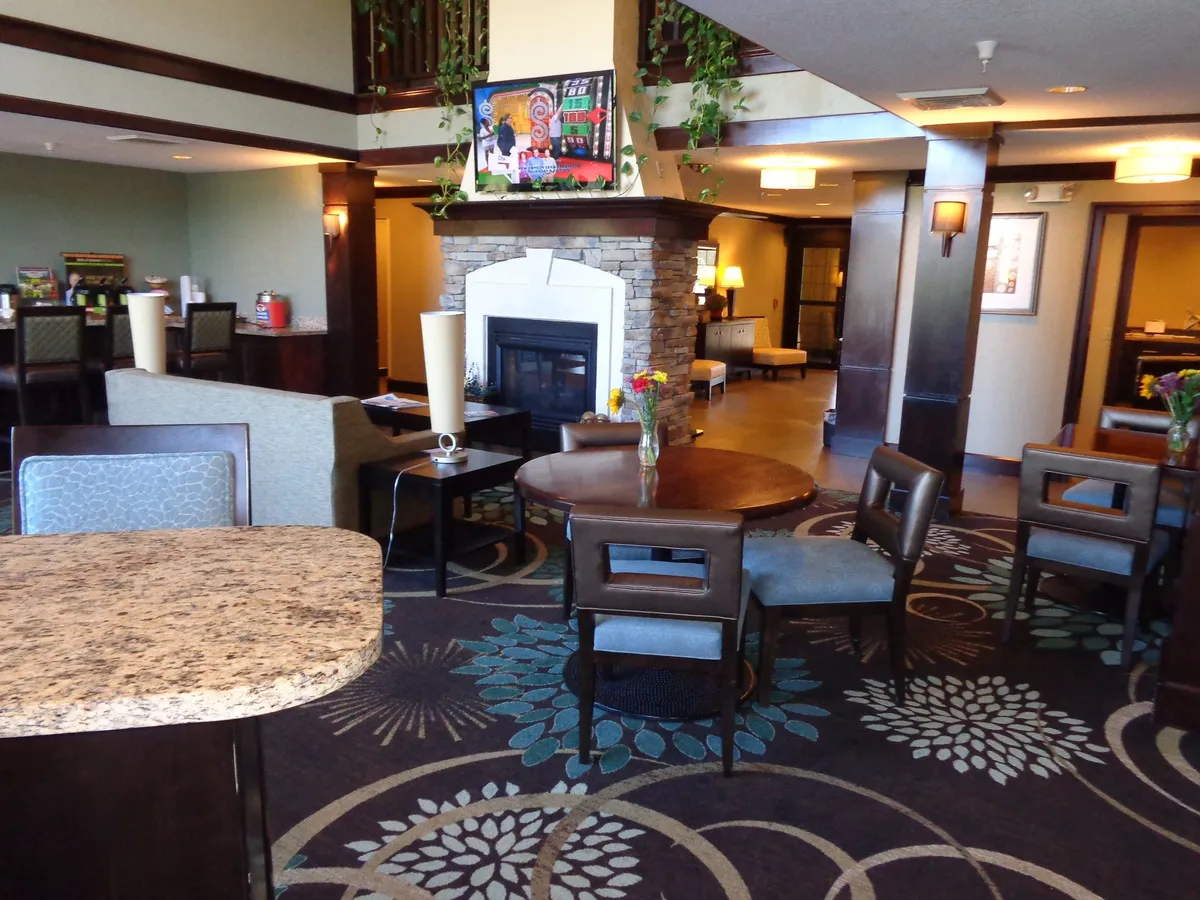 A welcoming living area centered around a fireplace, with a central table, vibrant decorative plants, and colorful artwork. This communal space is ideal for socializing, relaxing, or enjoying time together as a group.